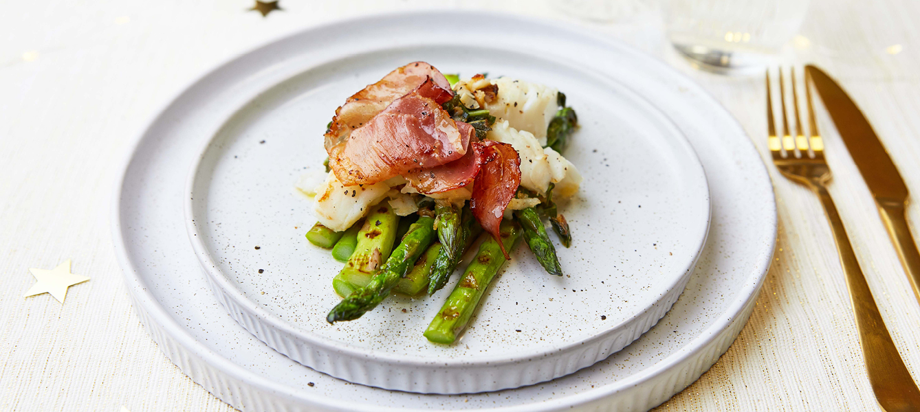 Kabeljau mit Salbeibutter auf einem Bett aus grünem Spargel